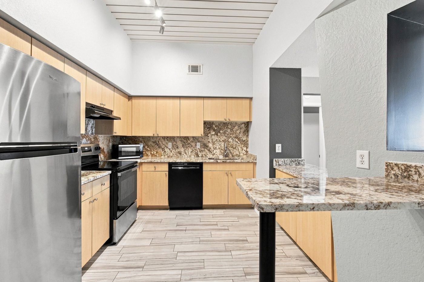 Kitchen with granite counters, a breakfast-bar island, light wood cabinetry and stainless steel appliances
